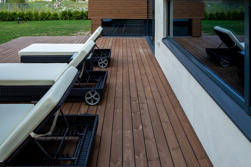Liegestühle auf einer modernen Holzterrasse mit Thermokiefer Terrassendielen