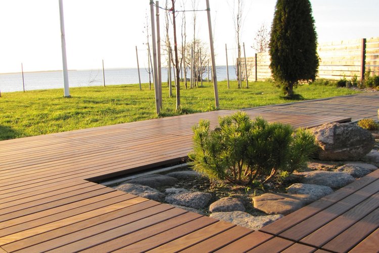 Terrasse im Herbst Eine Terrasse aus Holz im goldenen Herbstlicht, im Hintergrund Rasen, Bäume sowie See.