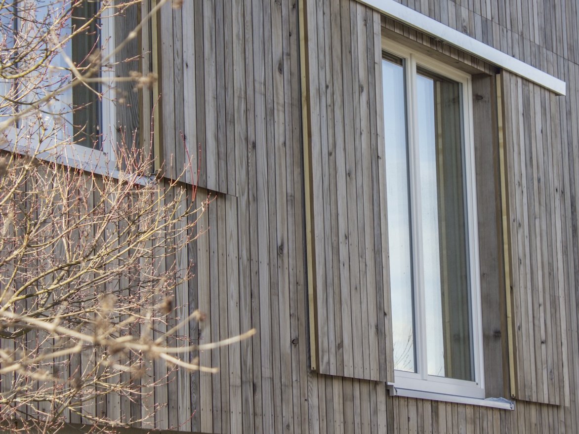 Eine moderne Holzfassade aus Grizawood mit großen Fenstern