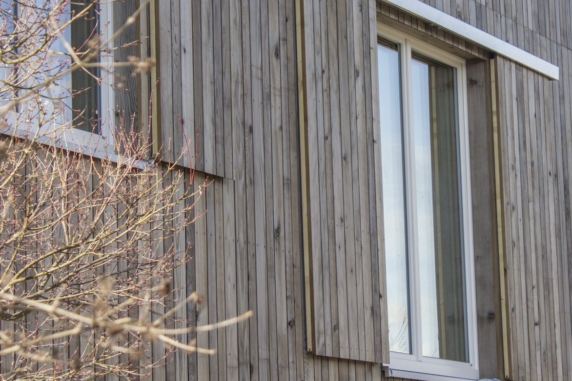 Fassade mit Fenstern Eine moderne Holzfassade aus Grizawood mit großen Fenstern