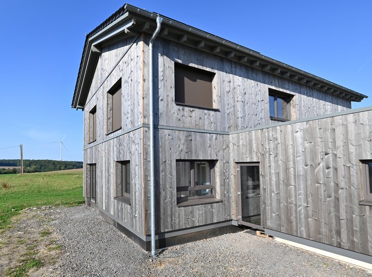Einfamilienhaus mit Holzfassade in ländlicher Umgebung.